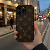 Hand holding a phone case with a pattern on a city street